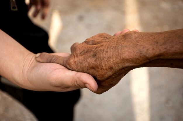Cuidador sosteniendo la mano de una persona con alzhéimer. Foto Freepick